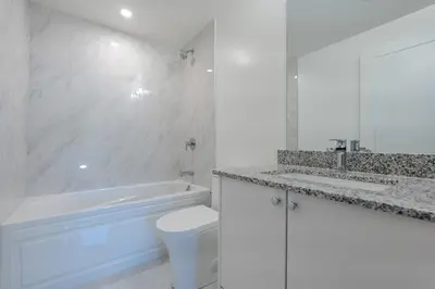 a white bathroom with a tub and a toilet and a sink at RivetStays - The Westmounts in Toronto