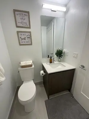 a bathroom with a toilet and a sink and a mirror at Serene Cozy 1BDRM Condo near Sherway Mall, Lakeshore, & Airport in Toronto