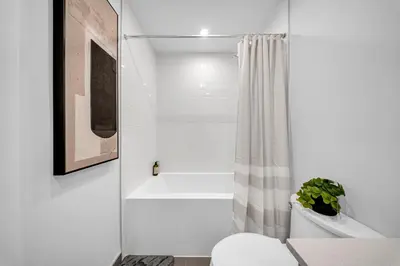 a white bathroom with a shower and a toilet at The Grand Aurelia Suites - Mississauga City Center in Mississauga
