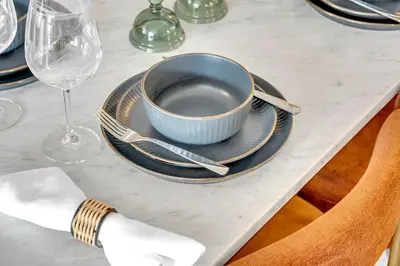 a table with a blue bowl and plates and wine glasses at The Grand Aurelia Suites - Mississauga City Center in Mississauga