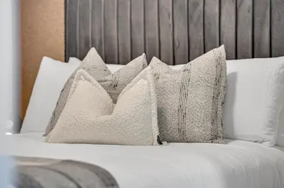 a pile of pillows sitting on a bed at The Grand Aurelia Suites - Mississauga City Center in Mississauga