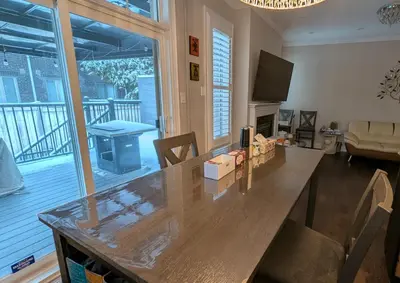 a living room with a large wooden table with a television at Bright ensuite with WiFi Parking available in Markham