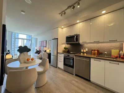 a kitchen with white cabinets and a table and chairs at Deluxe Suites & Towers Downtown Toronto in Toronto