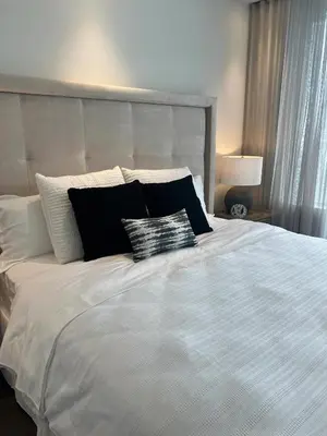 a bed with black and white pillows on it at Deluxe Suites & Towers Downtown Toronto in Toronto