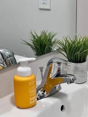 a bottle of sunscreen sitting on a bathroom sink at AyrHaus- Modern Comfort Meets Small-Town Charm