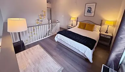 a bedroom with a bed and two lamps and a staircase at Slopeside Loft at North Creek Resort in Blue Mountains
