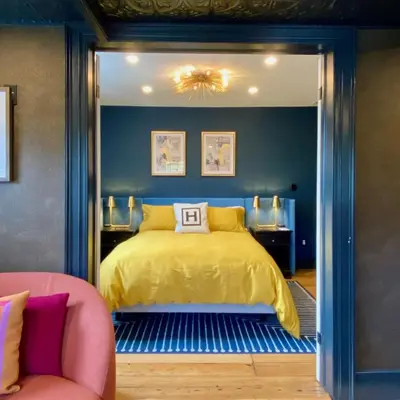 a bedroom with a yellow bed and a chair at Hattan House Boutique Hotel Bed & Breakfast in Niagara on the Lake