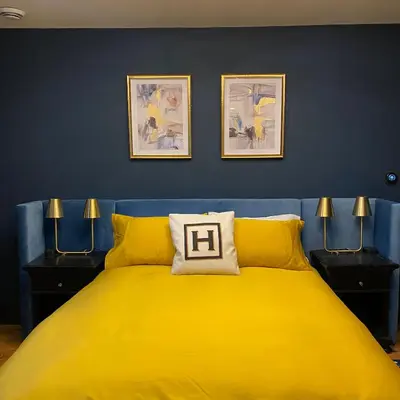 a bedroom with a yellow bed and two pictures on the wall at Hattan House Boutique Hotel Bed & Breakfast in Niagara on the Lake