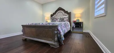 a bedroom with a large bed with a wooden headboard at Modern Cozy Nook in Brampton