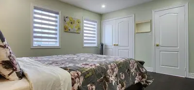 a bedroom with a bed and two windows at Modern Cozy Nook in Brampton