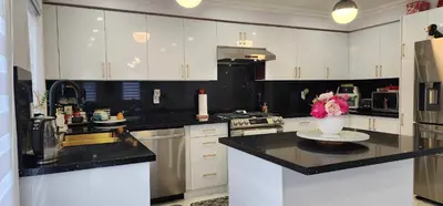 a kitchen with white cabinets and a vase of flowers on a counter at Modern Cozy Nook in Brampton