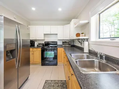 a kitchen with a stainless steel refrigerator and a sink at Lakefront Muskoka Cottage with Fire Pit and BBQ in Port Carling