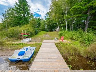 two boats sitting on a dock in the water at Lakefront Muskoka Cottage with Fire Pit and BBQ in Port Carling