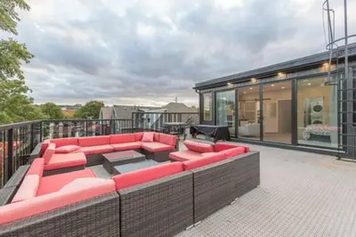 a patio with red couches on top of a building at Renovated Church Hamilton! Sleeps 10 Overnight! in Hamilton
