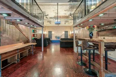 a large room with stairs and a bar with stools at Renovated Church Hamilton! Sleeps 10 Overnight! in Hamilton