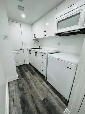 a kitchen with white cabinets and a sink and a microwave at Konia Abode in Orangeville