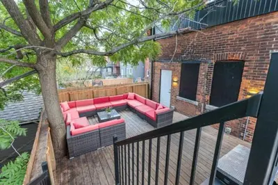 a red couch sitting on a deck next to a tree at Renovated Church Hamilton! Evening Event Rental! in Hamilton