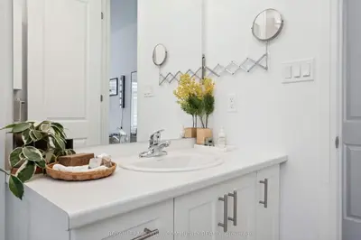 a white bathroom with a sink and a mirror at North City Haven - Cozy 2 Bedroom Retreat in Barrie