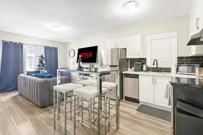 a kitchen with white cabinets and bar stools at 6BR Family Friendly Retreat, Separate Floors, 5 Minutes Walk to The Fallsview with Free Parking & Wine in Niagara Falls