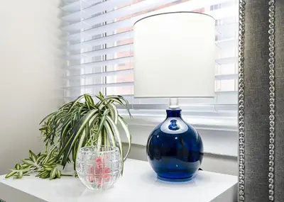 a blue vase sitting on a table with a lamp and a glass at 6BR Family Friendly Retreat, Separate Floors, 5 Minutes Walk to The Fallsview with Free Parking & Wine in Niagara Falls