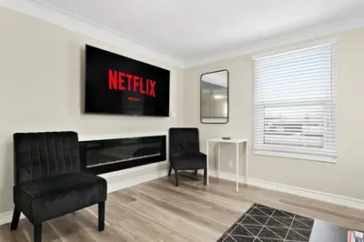 a living room with two chairs and a television at 6BR Family Friendly Retreat, Separate Floors, 5 Minutes Walk to The Fallsview with Free Parking & Wine in Niagara Falls