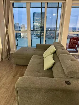 a living room with a couch and a large window at CN Tower and Rogers Centre View and Central Island Lake View in Toronto