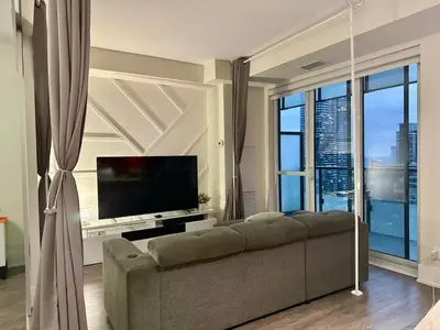 a living room with a couch and a flat screen tv at CN Tower and Rogers Centre View and Central Island Lake View in Toronto