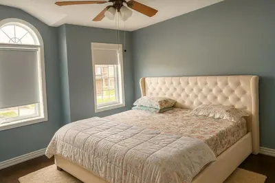 a bedroom with a bed with a ceiling fan and two windows at Cozy 3 Bed Whole Rental Home for your stay! in Brampton