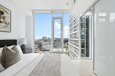 a bedroom with a large white bed and a large window at Luxury Downtown Stay with Spacious Patio in Toronto
