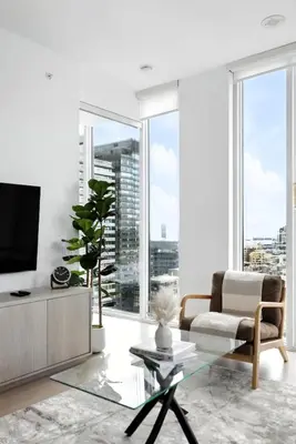 a living room with a couch and a tv and large windows at Luxury Downtown Stay with Spacious Patio in Toronto