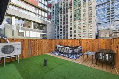 a deck with a table and chairs on a building at Modern Queen West Retreat Massive Patio 65 TV in Toronto