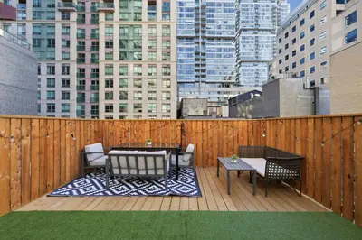 a patio with tables and chairs on a wooden fence at Modern Queen West Retreat Massive Patio 65 TV in Toronto