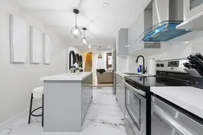 a kitchen with white counters and a stove top oven at Modern Queen West Retreat Massive Patio 65 TV in Toronto