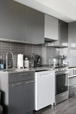 a kitchen with white appliances and gray cabinets at Bright Downtown Condo with City Views & Comfort in Toronto