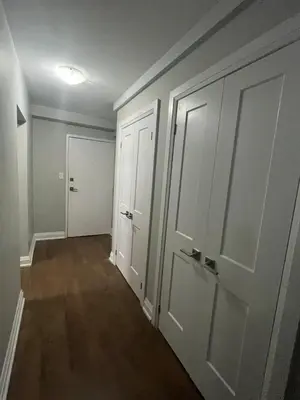an empty hallway with white doors and wood floors at Luxurious Two Bedroom Apartment in Burlington