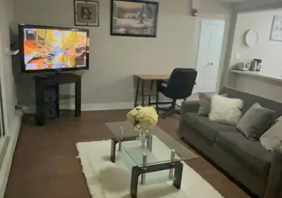 a living room with a couch and a tv at Luxurious Two Bedroom Apartment in Burlington