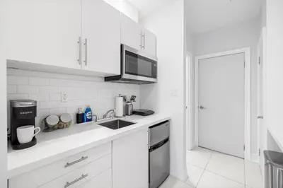 a white kitchen with a sink and a microwave at Stylish 2BR Retreat by Queen West in Toronto