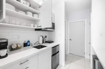 a white kitchen with white cabinets and a sink at Stylish 2BR Retreat by Queen West in Toronto