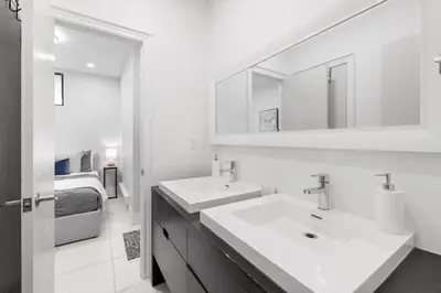 a white bathroom with two sinks and a bed at Stylish 2BR Retreat by Queen West in Toronto