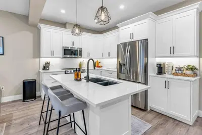 a kitchen with white cabinets and a kitchen island with bar stools at Cozy & Modern Home | EV Charger in Elmira