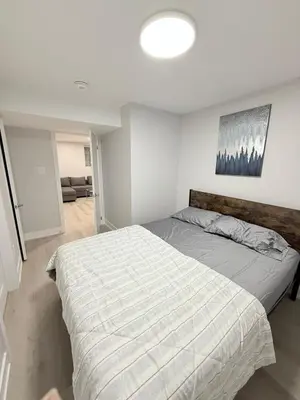 a bedroom with a bed with a striped comforter at Modern and Cozy Basement Suite,2 Bedrooms with Kitchen ,Parking and Separate Entrance in Milton