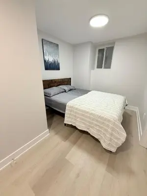 a bedroom with a bed in the corner of a room at Modern and Cozy Basement Suite,2 Bedrooms with Kitchen ,Parking and Separate Entrance in Milton