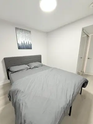 a white bedroom with a large bed in it at Modern and Cozy Basement Suite,2 Bedrooms with Kitchen ,Parking and Separate Entrance in Milton