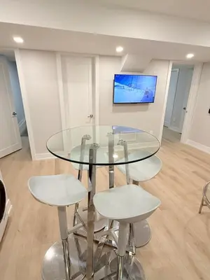 a glass table and stools in a room with a tv at Modern and Cozy Basement Suite,2 Bedrooms with Kitchen ,Parking and Separate Entrance in Milton