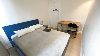 a bed with a blue headboard in a room with a desk at warm heart toronto in Toronto