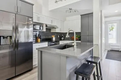 a kitchen with white cabinets and a stainless steel refrigerator at Townhouse with Hot Tub near Blue Mountain Village - 162 Vacation Inn in Collingwood