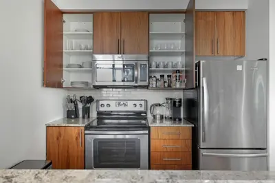 a kitchen with stainless steel appliances and wooden cabinets at Stylish Downtown - Condo Sleeps 8 - YYZ Airport in Mississauga