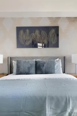 a bedroom with a large white bed with blue pillows at Stylish 2br High-Rise - Sleeps 7 - YYZ in Mississauga