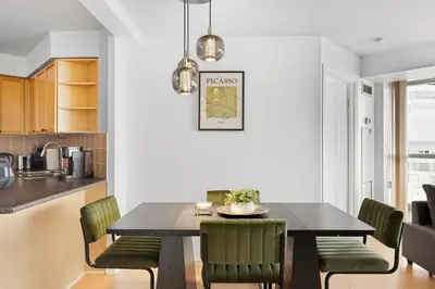 a dining room with a table and green chairs at Stylish 2br High-Rise - Sleeps 7 - YYZ in Mississauga
