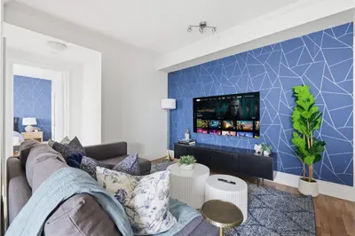 a living room with a couch and a tv on a blue wall at Stylish 3br Condo - Parking - 65 TV in Mississauga